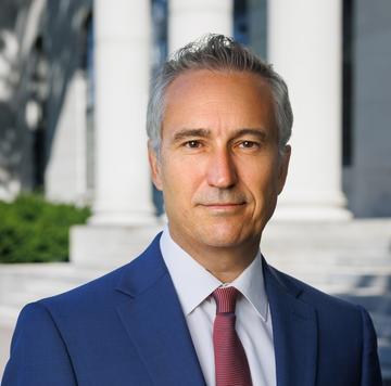 A man in a blue blazer and red tie looking into camera; Professor Pol Antràs.